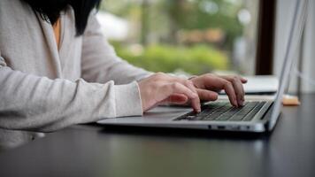 ein Frau Tippen auf ihr Laptop Klaviatur, Arbeiten auf ihr Laptop Computer beim ein Tabelle drinnen. foto