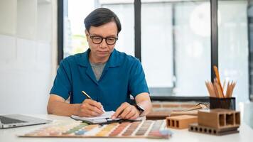 ein erfahren Senior asiatisch männlich Innere Designer oder Auftragnehmer ist Arbeiten im seine Büro. foto
