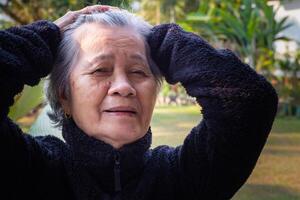 Porträt von ein glücklich Senior Frau Hände hoch, lächelnd und suchen beim das Kamera während Stehen im ein Garten. Raum zum Text. Konzept von alt Menschen und Gesundheitswesen foto