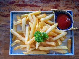 oben Aussicht von Französisch Fritten und Kartoffeln Soße auf ein Teller auf ein alt hölzern Tisch. Snack Lebensmittel bunt und selektiv Fokus foto