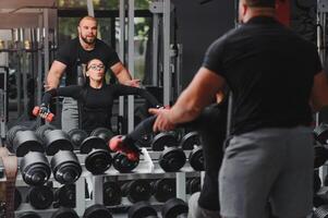 Fitness, Sport, Übungen und Gewichtheben. Konzept - - ein jung Frau und ein jung Mann mit Hanteln fegen Muskeln im das Fitnessstudio foto