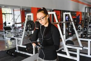 Porträt von jung Sportlerin mit Smartphone Hören zu Musik- im Fitnessstudio. foto