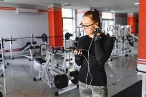 jung lächelnd Frau Hören zu Musik- auf Smartphone beim das Fitnessstudio foto