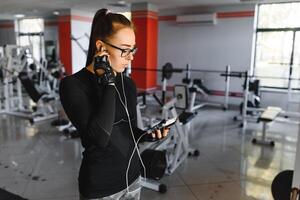 jung lächelnd Frau Hören zu Musik- auf Smartphone beim das Fitnessstudio foto