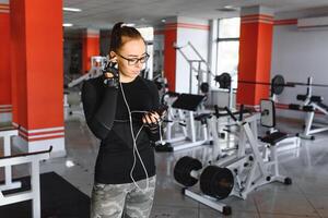 jung lächelnd Frau Hören zu Musik- auf Smartphone beim das Fitnessstudio foto