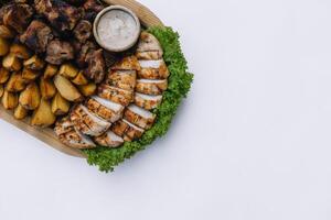 die meisten Fleisch Gericht - - Rindfleisch Kebabs, Würste, gegrillt Pilze, Kartoffeln, Tomaten und Soße. das Beste Wahl zum ein Bier. Nahansicht auf ein Weiß Hintergrund foto