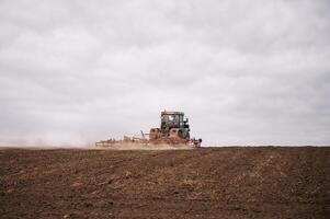Farmer im Traktor vorbereiten Land mit Saatbeet Grubber im Ackerland. foto