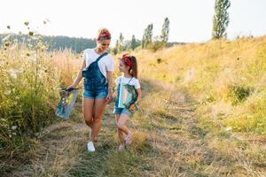 Schönheit Mutter Farbe mit ihr wenig Tochter. stilvoll Frau Zeichnung das Bild mit wenig Mädchen. süß Kind im ein Weiß T-Shirt und Blau Jeans. Mutter Tag. foto