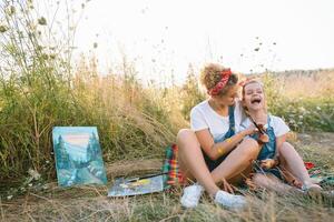 Mutter unterrichtet Tochter Farbe im Park. sonnig Natur, Mama und Tochter Farbe ein Bild im ein Park , Gemälde ein wenig Kind, Kind Kreativität. Mutter Tag. foto