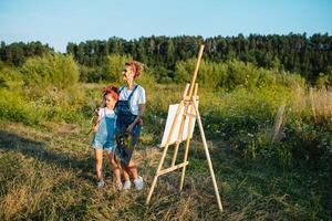 Mutter unterrichtet Tochter Farbe im Park. sonnig Natur, Mama und Tochter Farbe ein Bild im ein Park , Gemälde ein wenig Kind, Kind Kreativität. Mutter Tag. foto