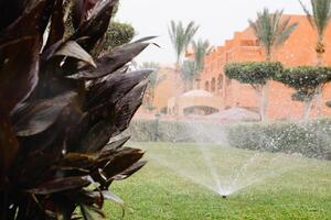 modern Gerät von Bewässerung Garten. Bewässerung System - - Technik von Bewässerung im das Garten. Rasen Sprinkler Sprühen Wasser Über Grün Gras. foto