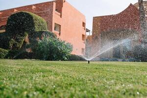 modern Gerät von Bewässerung Garten. Bewässerung System - - Technik von Bewässerung im das Garten. Rasen Sprinkler Sprühen Wasser Über Grün Gras. foto
