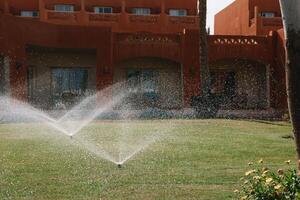 automatisch Sprinkler System Bewässerung das Rasen auf ein Hintergrund von Grün Gras, Nahansicht foto