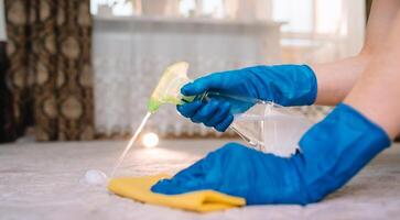 Menschen, Hausarbeit und Hauswirtschaft Konzept - - schließen oben von Frau im Gummi Handschuhe mit Stoff und derergent sprühen Reinigung Teppich beim heim. schließen oben von Frau mit Stoff Reinigung Teppich foto