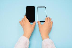 Smartphone mit Bildschirm schützen Glas Startseite im Hände. Blau Hintergrund. Frauen Hand Stock temperiert Glas Schild oder Film Bildschirm Startseite mit Handy, Mobiltelefon Telefon. Schutz Konzepte Ideen foto