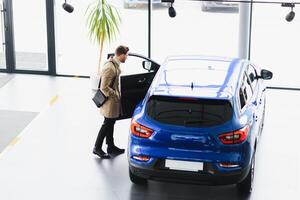 jung gut aussehend Mann beim Show Zimmer Stehen in der Nähe von Auto foto