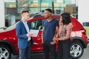 Verkäufer zeigen Neu Auto zu afrikanisch Paar im Ausstellungsraum foto