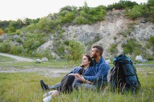 ein Paar von Touristen im Zeit von Ausflug Stahl und bewundern das schön Berg Landschaft. das Kerl Umarmungen das Mädchen. das Konzept von Liebe, Zärtlichkeit und Erholung foto