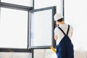 männlich industriell Baumeister Arbeiter beim Fenster Installation im Gebäude Konstruktion Seite? ˅ foto