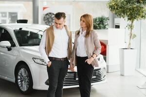 jung Paar kaufen ein Auto im ein Auto Ausstellungsraum. foto