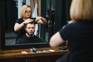 Barbier Frau Schneiden Mann Haar beim das Friseurladen. Frau Arbeiten wie ein Friseur. klein Geschäft Konzept foto