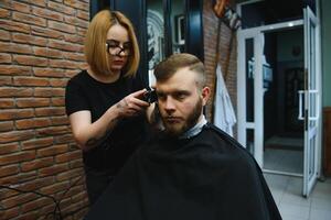 Barbier Frau Schneiden Mann Haar beim das Friseurladen. Frau Arbeiten wie ein Friseur. klein Geschäft Konzept foto