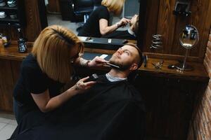 Friseur oder Friseur Konzept. Frau Friseur schneidet Bart mit Schere. Mann mit lange Bart, Schnurrbart und stilvoll Haar. Kerl mit modern Frisur Besuch Friseur foto