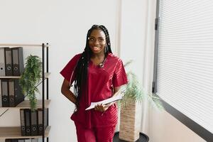 ein afrikanisch amerikanisch weiblich medizinisch Arzt mit ein Stethoskop im Krankenhaus. foto