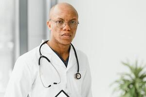 afrikanisch amerikanisch Mann männlich Krankenhaus Arzt im Weiß Mantel mit Stethoskop. foto