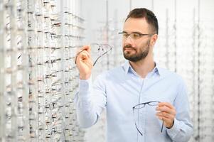 jung Mann wählen Brille beim Optik Geschäft foto