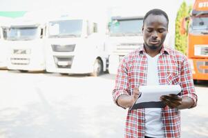 Porträt afrikanisch männlich glücklich lächelnd zuversichtlich positiv in der Nähe von LKW. jung Mann Plaid Hemd Inhaber LKW Treiber im Geschäft lange Transport Daumen oben zufrieden Bedienung kommerziell Fahren Lizenz Ausbildung foto