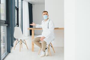 männlich Arzt in der Nähe von Rezeption Schreibtisch im Klinik foto