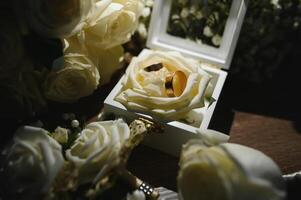 Gold Ringe und ein schön Braut- Strauß von Rosen auf das Hintergrund. Einzelheiten, Hochzeit Traditionen. Nahaufnahme, Makro. foto