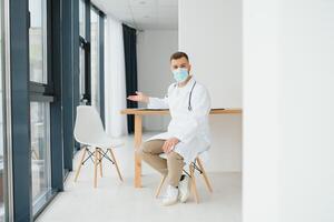 jung Arzt Sitzung im seine Büro hinter ein Schreibtisch foto