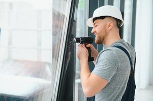 Konstruktion Arbeiter mit bohren während Installation Fenster drinnen foto