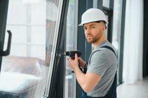 Konstruktion Arbeiter mit bohren während Installation Fenster drinnen foto