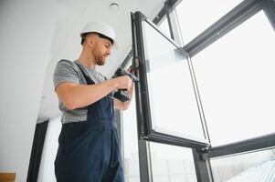 Arbeiter im Overall Installation oder einstellen Plastik Fenster im das Leben Zimmer beim Zuhause foto