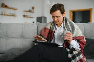 Porträt der schönen alten Frau mit Tablette PC und lächelnd, auf dem Sofa zu Hause sitzend foto