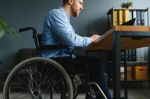 jung glücklich Unternehmer im Rollstuhl Arbeiten auf Laptop beim Zuhause foto