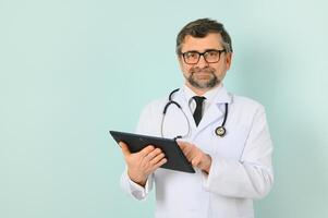lächelnd medizinisch Senior Arzt mit ein Stethoskop. auf ein Blau Hintergrund. das Konzept von der Menschheit Sieg Über Krankheit foto