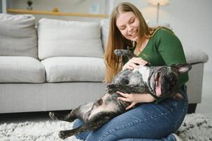 schön Mädchen, lächelnd und Sitzung auf Fußboden in der Nähe von Französisch Bulldogge foto