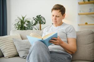 Frau im Zuhause Sitzung auf Sofa lesen Buch. foto