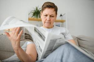 Frau lesen Zeitung beim Zuhause foto