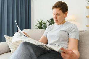 Frau lesen Zeitung beim Zuhause foto