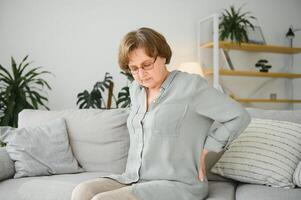 Senior Frau Leiden von Rückenschmerzen beim Zuhause foto