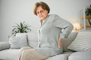 reifen Dame Sitzung auf Bett und berühren ihr zurück, Radikulitis und Schmerzen foto