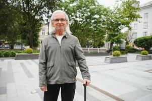 Alten Mann Spaziergänge mit ein Stock im ein Stadt Frühling Park. foto