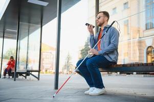 blind Mann mit Weiß Stock warten zum Öffentlichkeit Transport im Stadt. foto