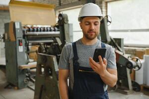 Verwaltung Team, Ingenieur, oder Vorarbeiter. Stehen Überprüfung Job Information Über industriell Produktion Verwaltung innerhalb das Fabrik durch Telefon. Zusammenarbeit Konzept foto