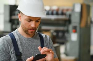 Verwaltung Team, Ingenieur, oder Vorarbeiter. Stehen Überprüfung Job Information Über industriell Produktion Verwaltung innerhalb das Fabrik durch Telefon. Zusammenarbeit Konzept foto